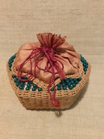 Old wicker basket with ready-made crocheted tablecloths inside with a bobbin with several crochet hooks and other crochet needles