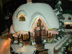 Új, Karácsonyi hangulatú havas ház különböző fényekkel világítva.