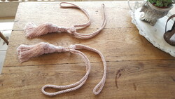 A pair of large, elegant powder-colored curtain ties