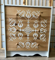 Dresser with three drawers decorated with a cross stitch pattern