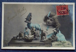 Antique Christmas greeting photo postcard of a little girl playing with Nativity scenes