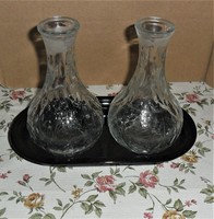 2 oil/vinegar bottles on an oval tupperware tray.