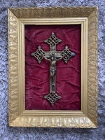 Metal cross in a wooden frame with a ring on burgundy velvet.