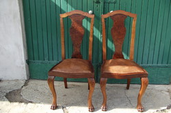 A pair of chairs with root veneer and leather seats.