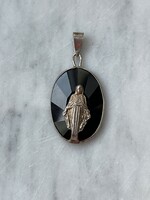 Dreamy silver Virgin Mary pendant on a black polished stone.