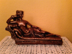 Bronzszínű szófán fekvő női akt szobor