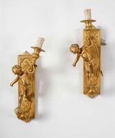 A pair of gilded bronze wall arms with putto figures