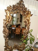 Hand-carved gold-colored, baroque-style mirror decorated with an angel figure and other motifs