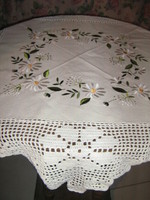 A beautiful hand-crocheted tablecloth with a daisies embroidered with floral edges
