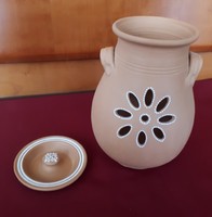 An unglazed ceramic pot with a lid and pierced sides