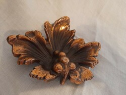 Old metal work, perhaps an ornament in the shape of a bronze grape leaf, an ashtray