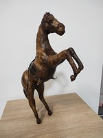 A carved, prancing horse, wooden statue with leather decoration