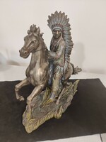 An Indian on a horse in a long feather ornament