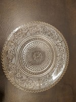 A very old glass cake plate with relief pattern and jagged edges