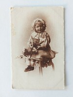 Old postcard photo of little girl with flowers and bonbons