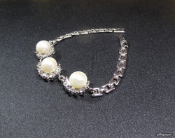 Akoya salt water cultured pearl set in medical grade metal bracelet with crystals around it.