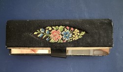 A small mirror in an embroidered holder