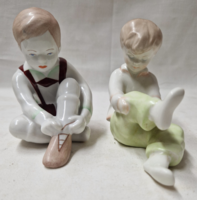 Aquincumi cipőjét kötöző fiú és zokniját húzó lány porcelán figurák hibátlan állapotban együtt