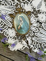 Old holy picture in a small oval metal frame with hanger