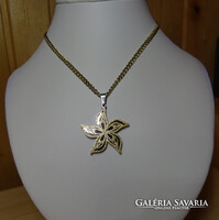 Medál és lánc sebészeti acélból virág alakban, hullámos szirmokkal az arany szín homok szórt.