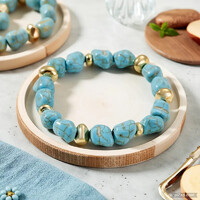 Eye-catching bracelet made of artificial turquoise beads, polished, with two gold-colored decorations