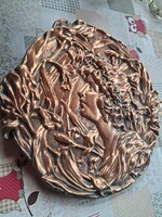 Dombornyomott, rézszínű falitányér vagy falidísz, amely szecessziós (Art Nouveau) stílusú női alakot