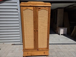 Eladó egy BRANDON  fiokos , polcos és akasztós rattan betétes fenyő szekrény.