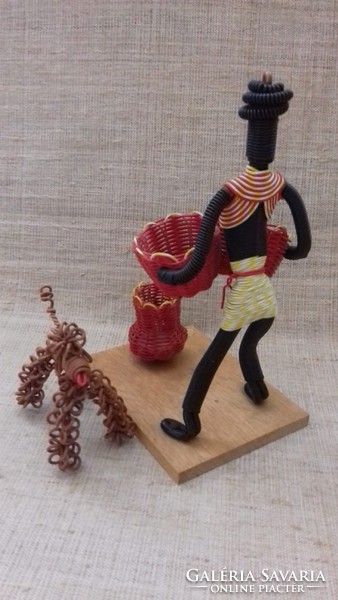A bent negro female figure with a basket and a dog, handmade from retro marked wire