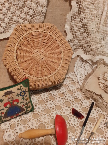 Old wicker basket with ready-made crocheted tablecloths inside with a bobbin with several crochet hooks and other crochet needles