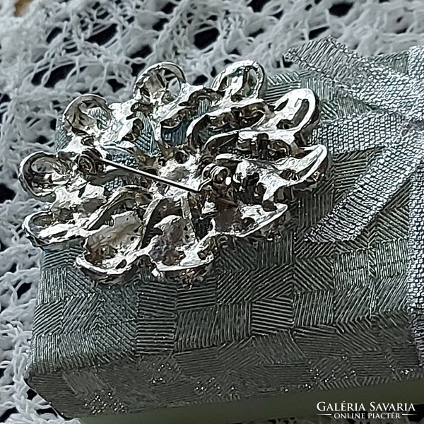 A beautiful brooch badge decorated with blue rhinestones embedded in a silver-plated metal alloy