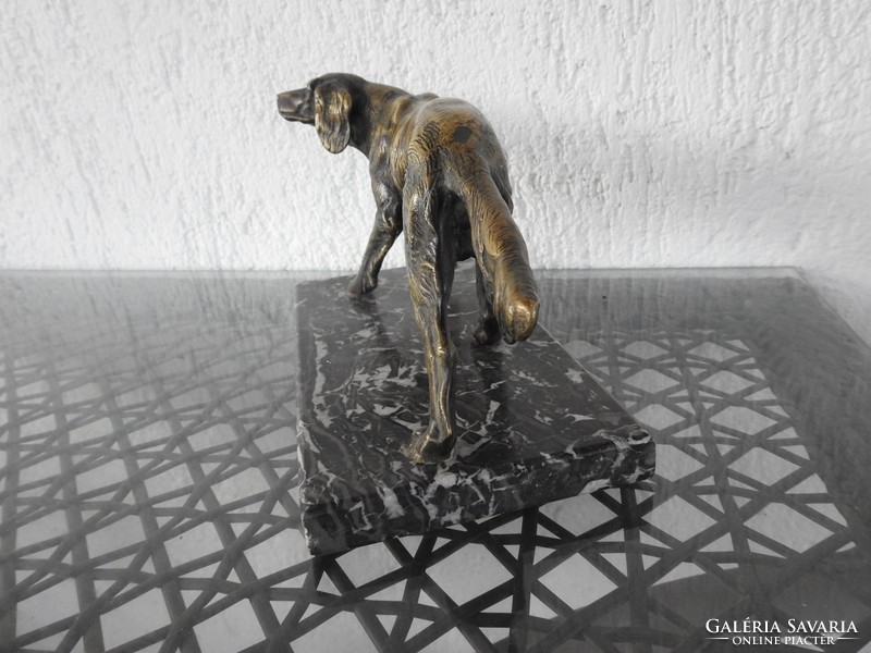 Large bronze dog sculpture on a marble pedestal