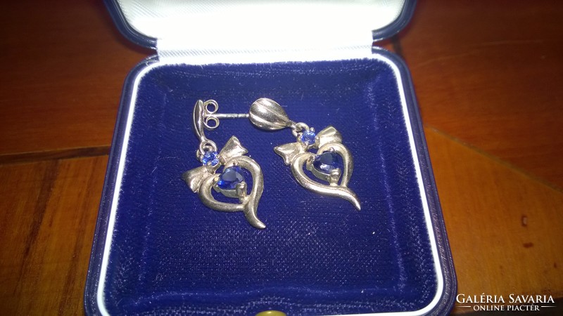 Silver bow earrings with blue stone-studded ears