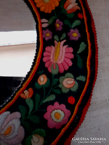 A mirror that can be hung on a wall with old matyó embroidery on an old cloth base