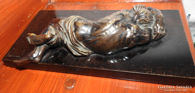 Lying suffering Jesus Christ - bronze statue on a wooden foundation