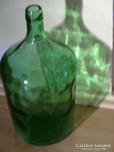 Fresh green glass old demison bottle with lens 5 l. Its silhouette highlights the dotted pattern in the glass