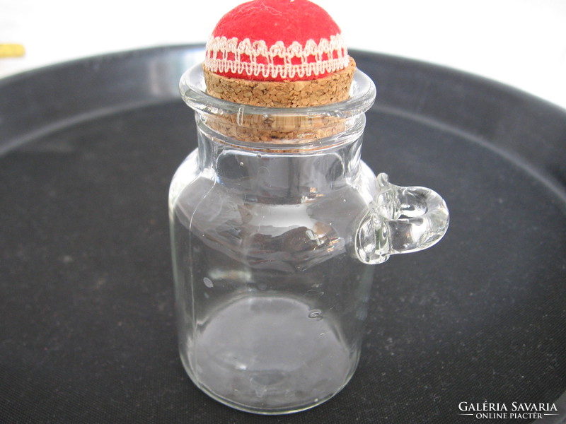 A small single-eared glass bottle with a spicy, decorated cork stopper