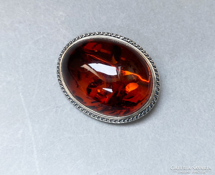 Large, showy silver brooch with amber.