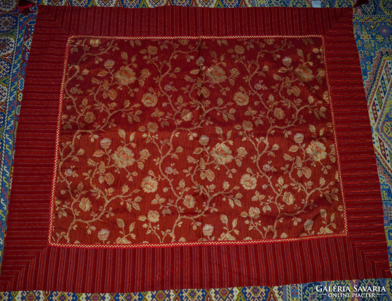 A tablecloth with a pattern woven in its material with a single tassel at the corners