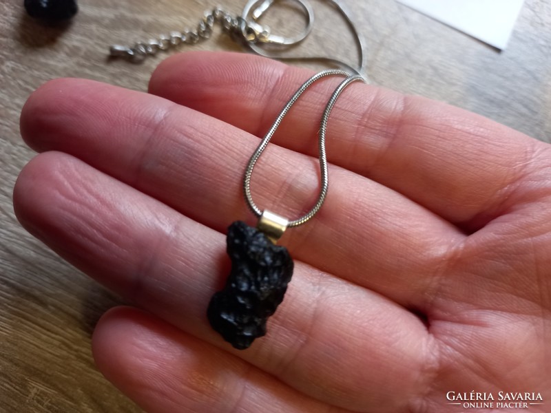 A piece of raw tektite meteorite on a silver clasp and silver chain