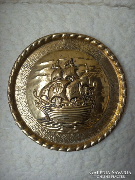 A copper wall plate with a convex ship image
