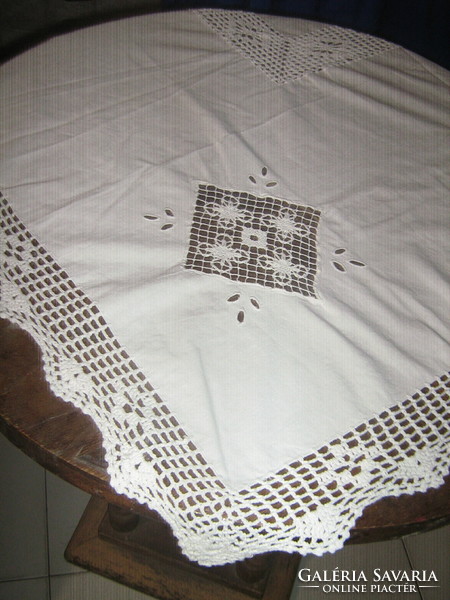 A dreamy white needlework tablecloth with a sewn lace insert with a hand-crocheted edge