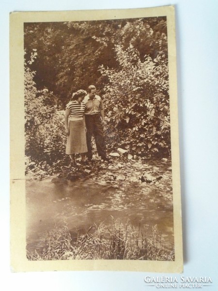 D195648 young couple on a stream bank - postcard 1950k