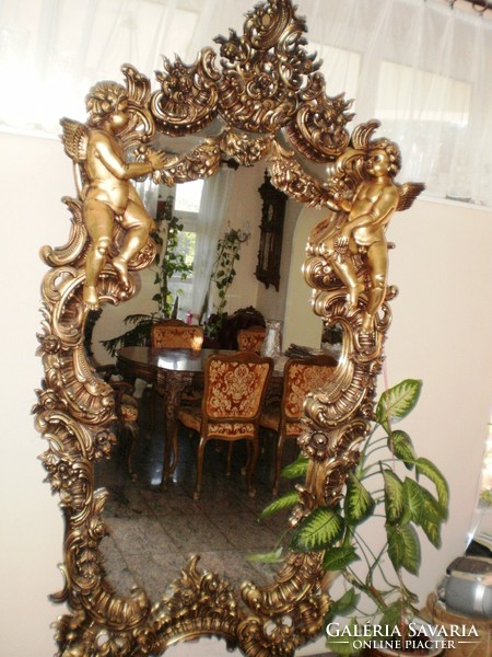 Hand-carved gold-colored, baroque-style mirror decorated with an angel figure and other motifs