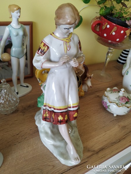 Porcelain figure of a girl picking flowers, in folk costume for sale!
