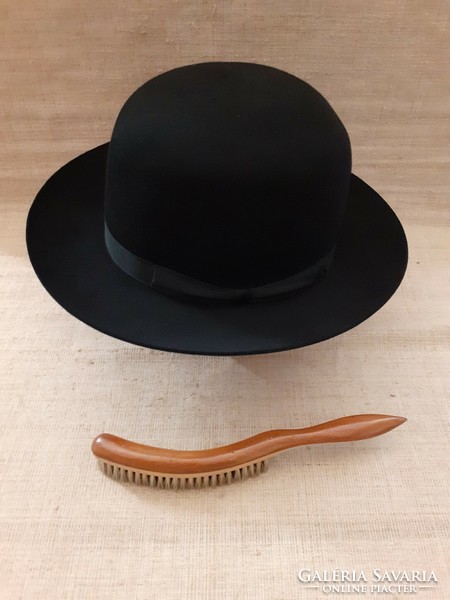 A well-maintained black branded hat with a horsehair hat brush with a wooden handle