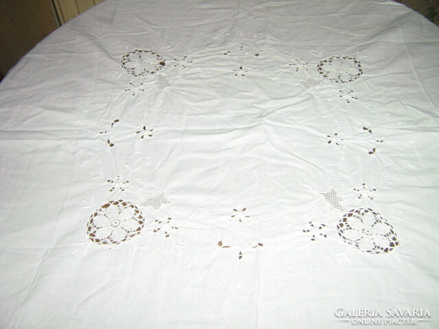 A dreamy white madeira embroidered tablecloth with a hand-crocheted edge and floral pattern insert
