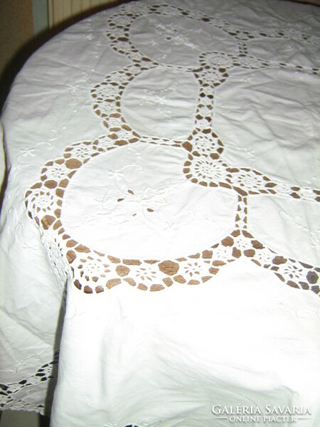 A dreamy white madeira embroidered tablecloth with a hand-crocheted flower pattern edge and inlay