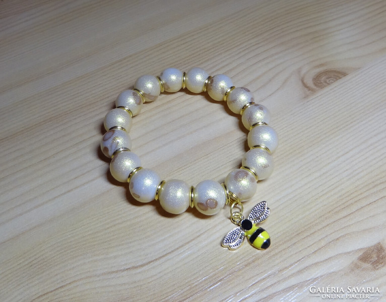 Gold-plated quality glass pearl bracelet on a white background, fire enamel with bee, gold spacers