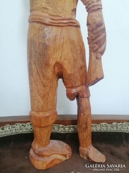 A large wooden statue of a fisherman with the caught fish on his harpoon
