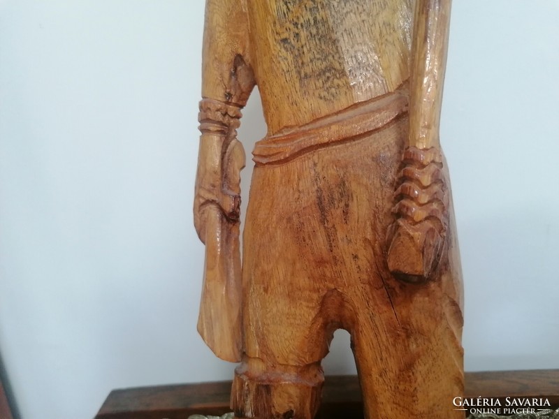 A large wooden statue of a fisherman with the caught fish on his harpoon